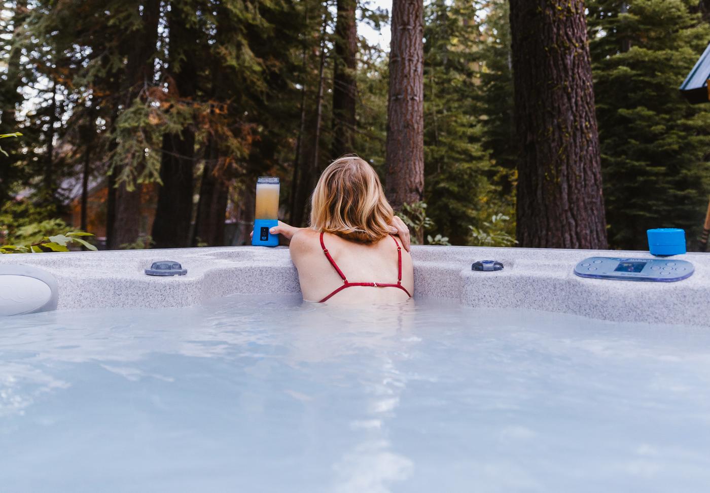 woman on the side of a hot tub looking into a forest